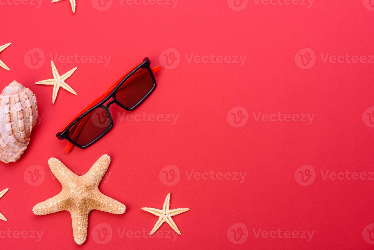 Glasses and hat with shells and sea stars on a colored background photo