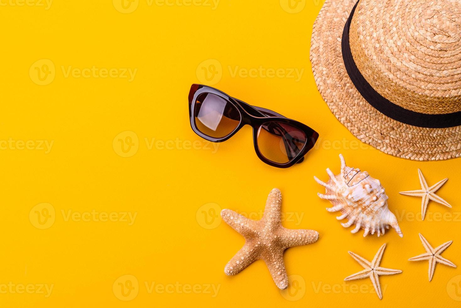 Glasses and hat with shells and sea stars on a colored background photo