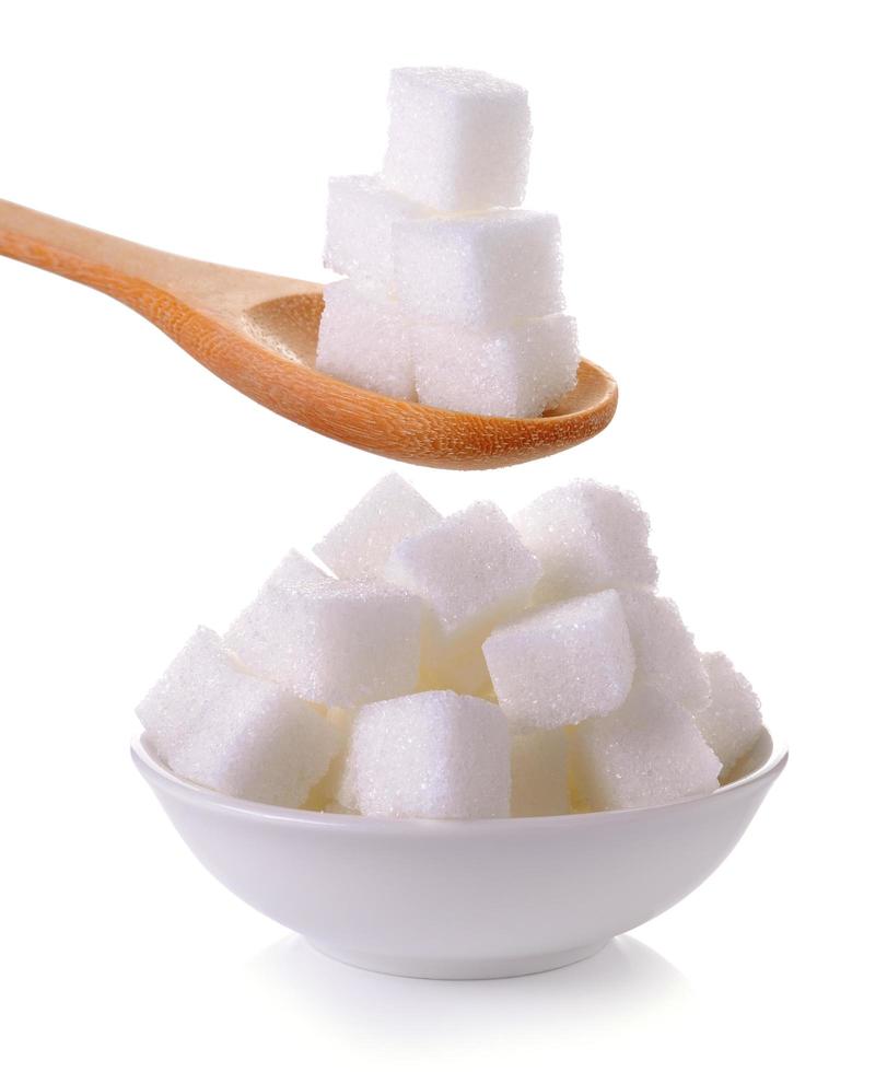 Sugar cube in the spoon and bowl on white background photo