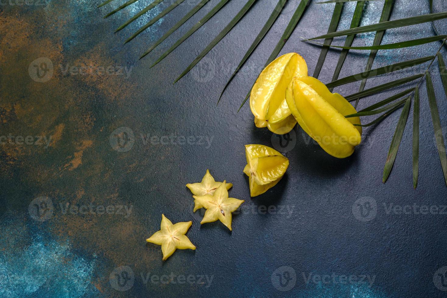 Fruit carambol, beach accessories and foliage of a tropical plant on colored paper photo