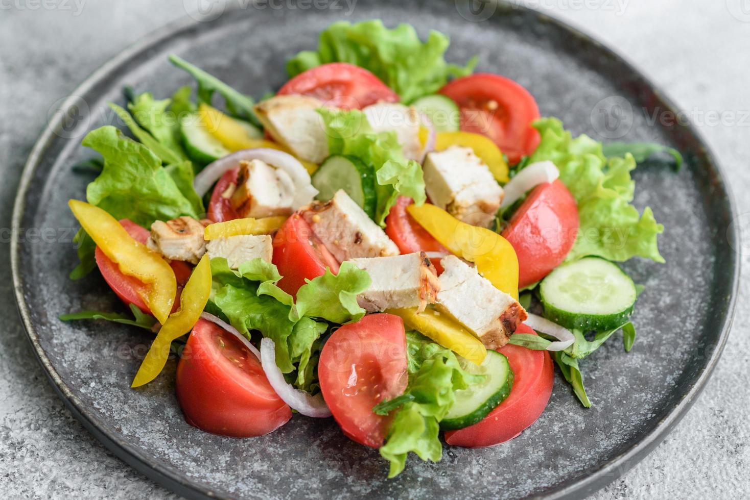 Fresh delicious salad with chicken, tomato, cucumber, onions and greens with olive oil photo