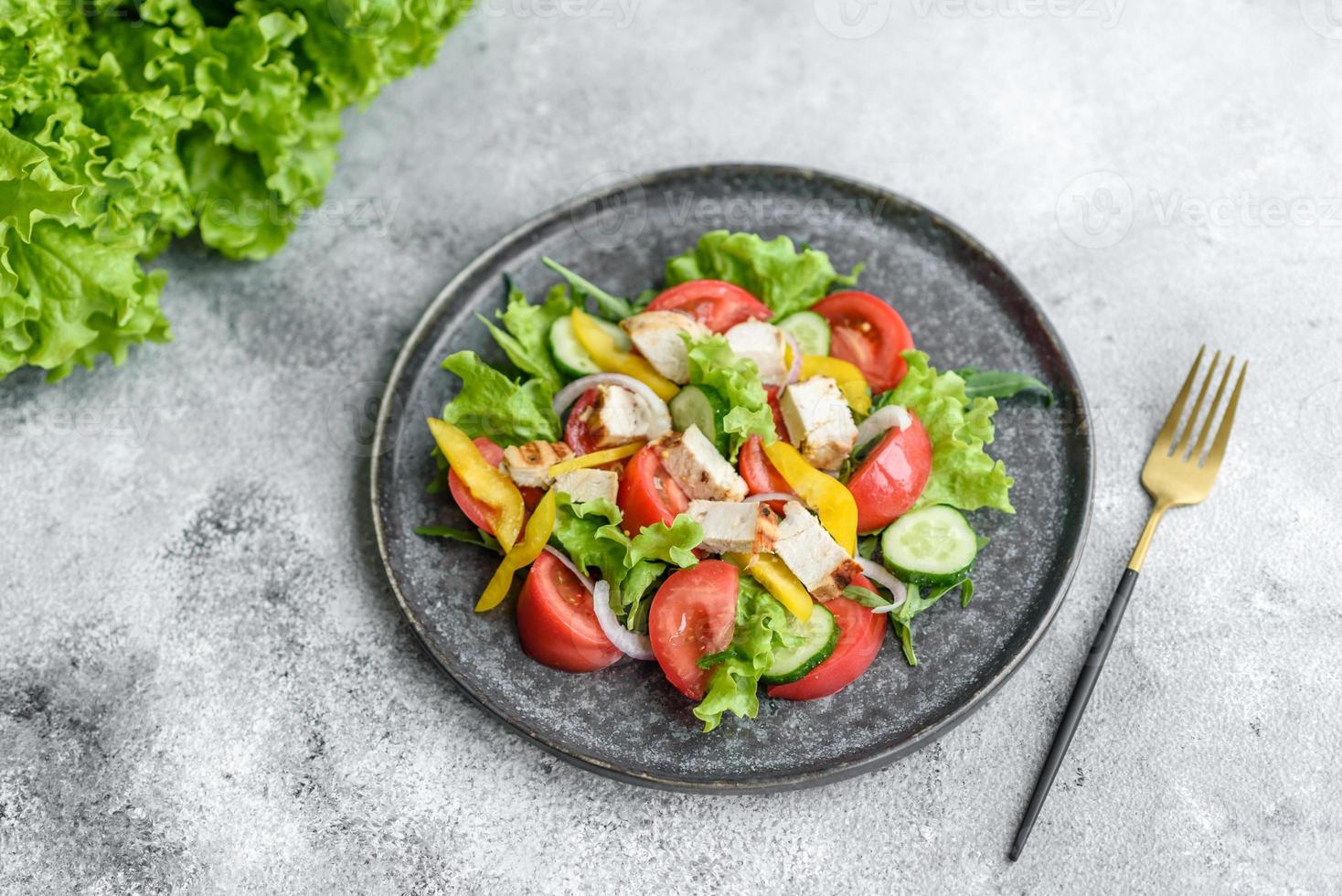 Fresh delicious salad with chicken, tomato, cucumber, onions and greens with olive oil photo