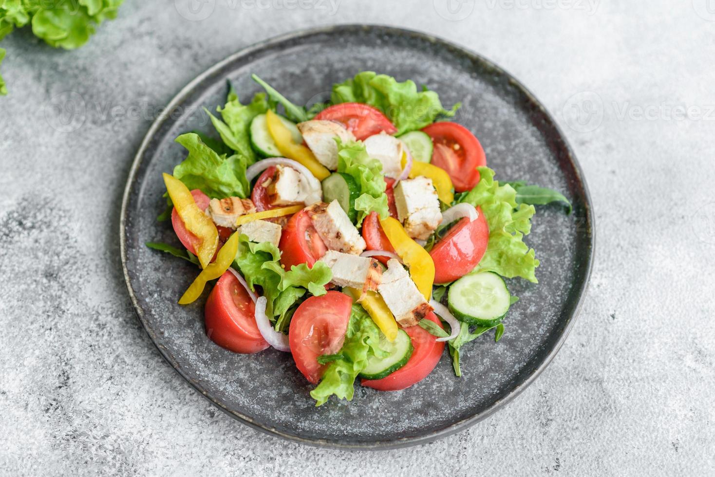 Fresh delicious salad with chicken, tomato, cucumber, onions and greens with olive oil photo