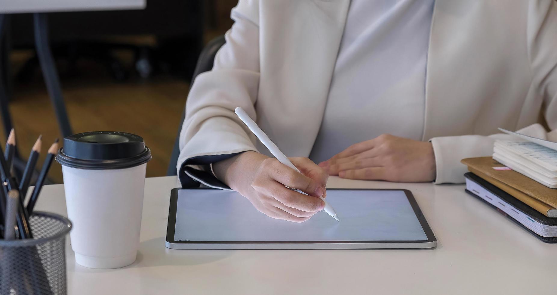 Mujer sosteniendo tableta digital con pantalla en blanco y lápiz óptico foto