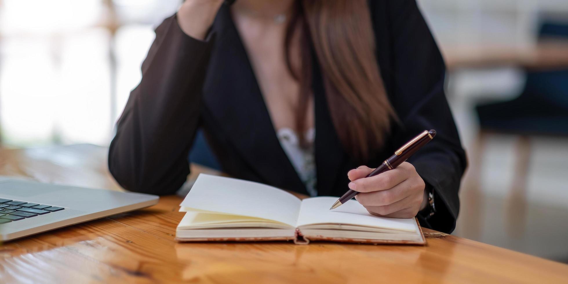 Close up woman's hands with laptop, notebook and pen photo