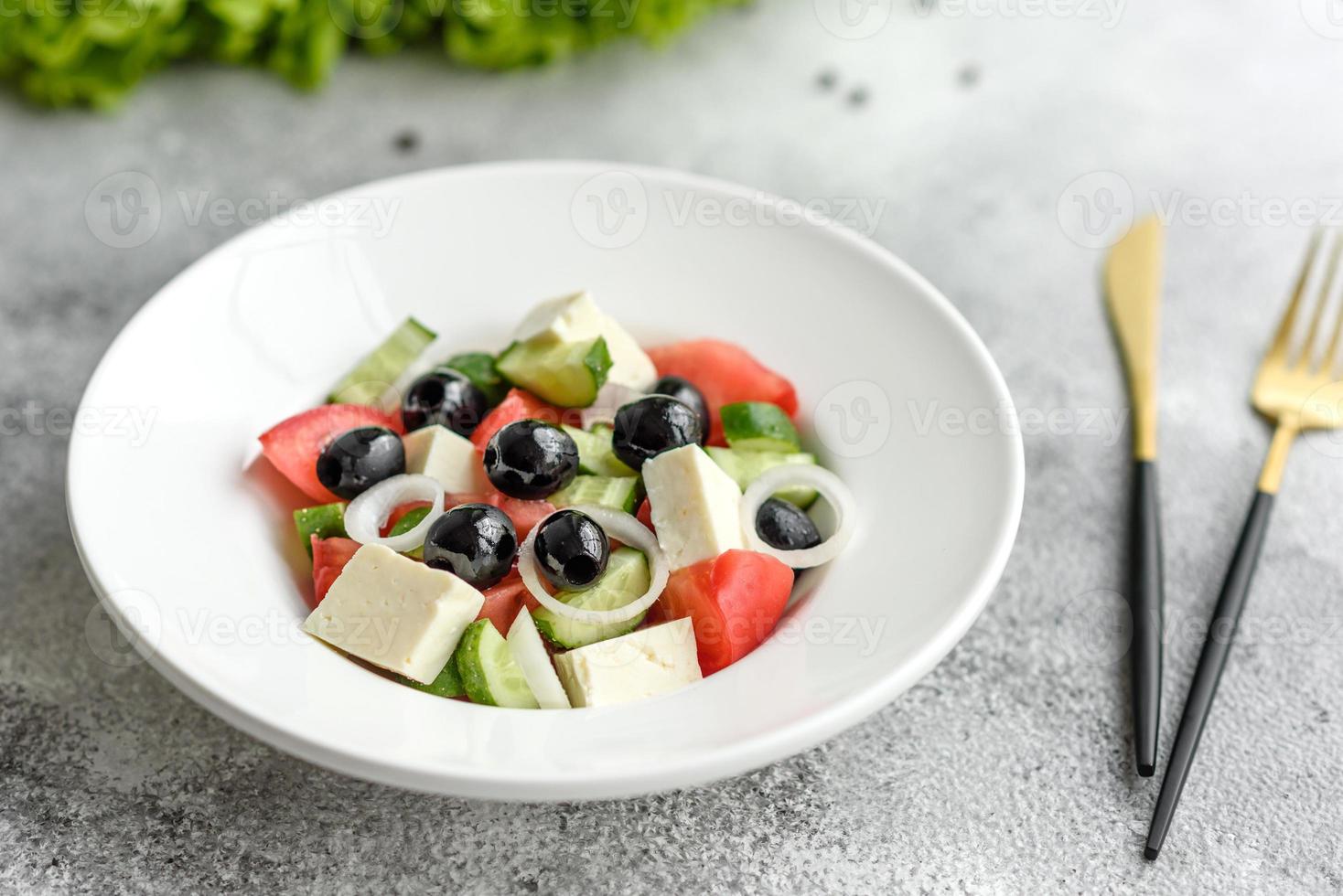 Fresh delicious Greek salad with tomato, cucumber, onions and olives with olive oil photo