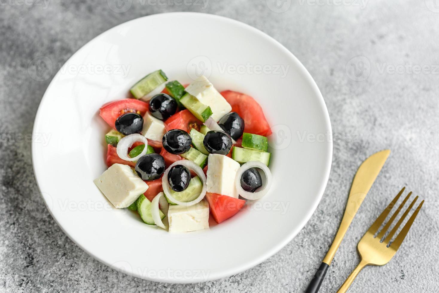 Fresh delicious Greek salad with tomato, cucumber, onions and olives with olive oil photo