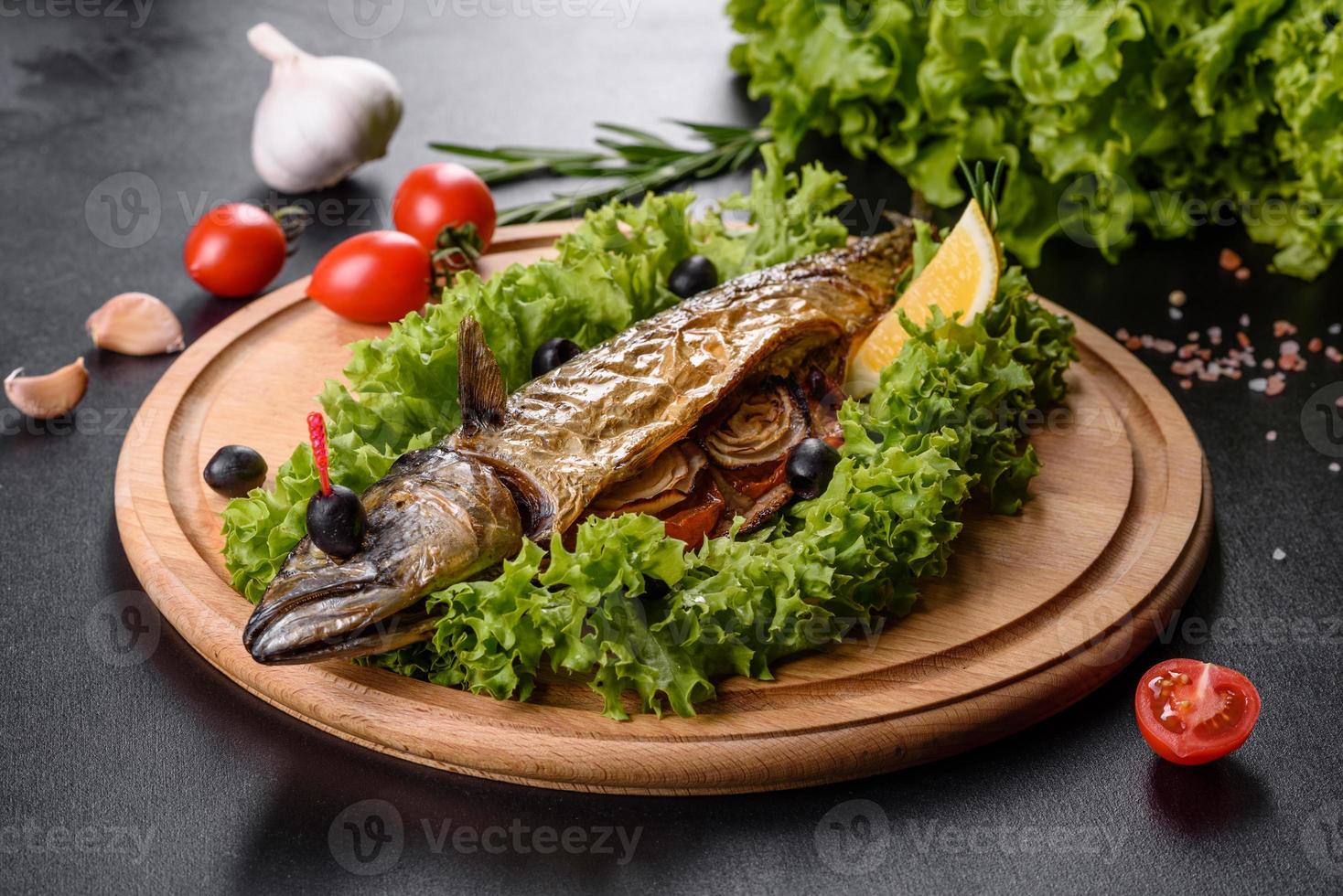 Baked mackerel with vegetables on a wooden board with lemon photo