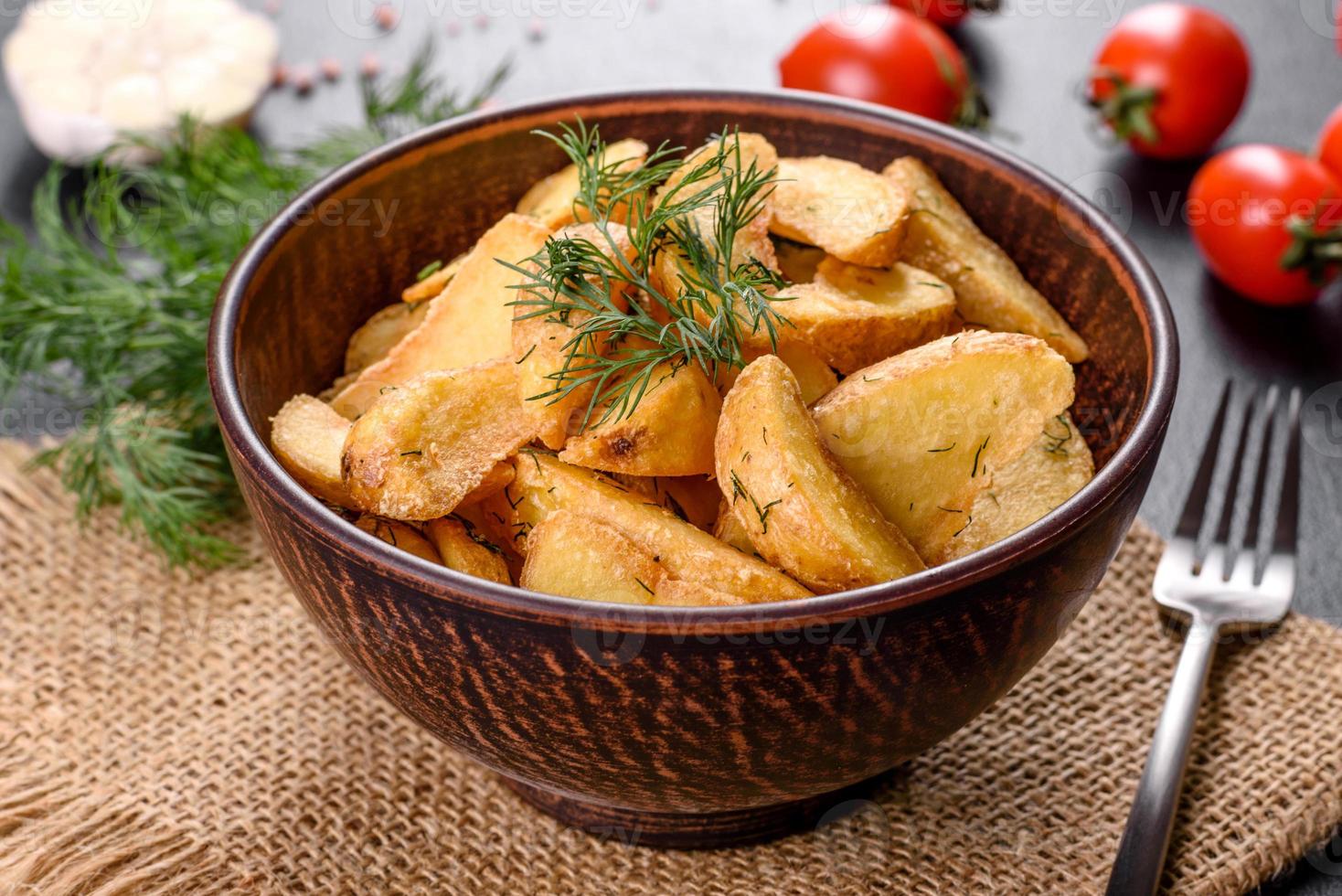 Tasty baked potatoes in a rustic way with spices and herbs in a brown deep plate photo