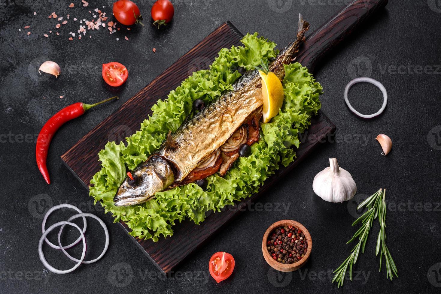 Baked mackerel with vegetables on a wooden board with lemon photo