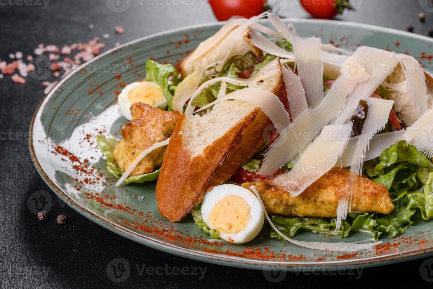 deliciosa ensalada César fresca con carne de pollo, pan rallado, tomates y hojas de lechuga foto