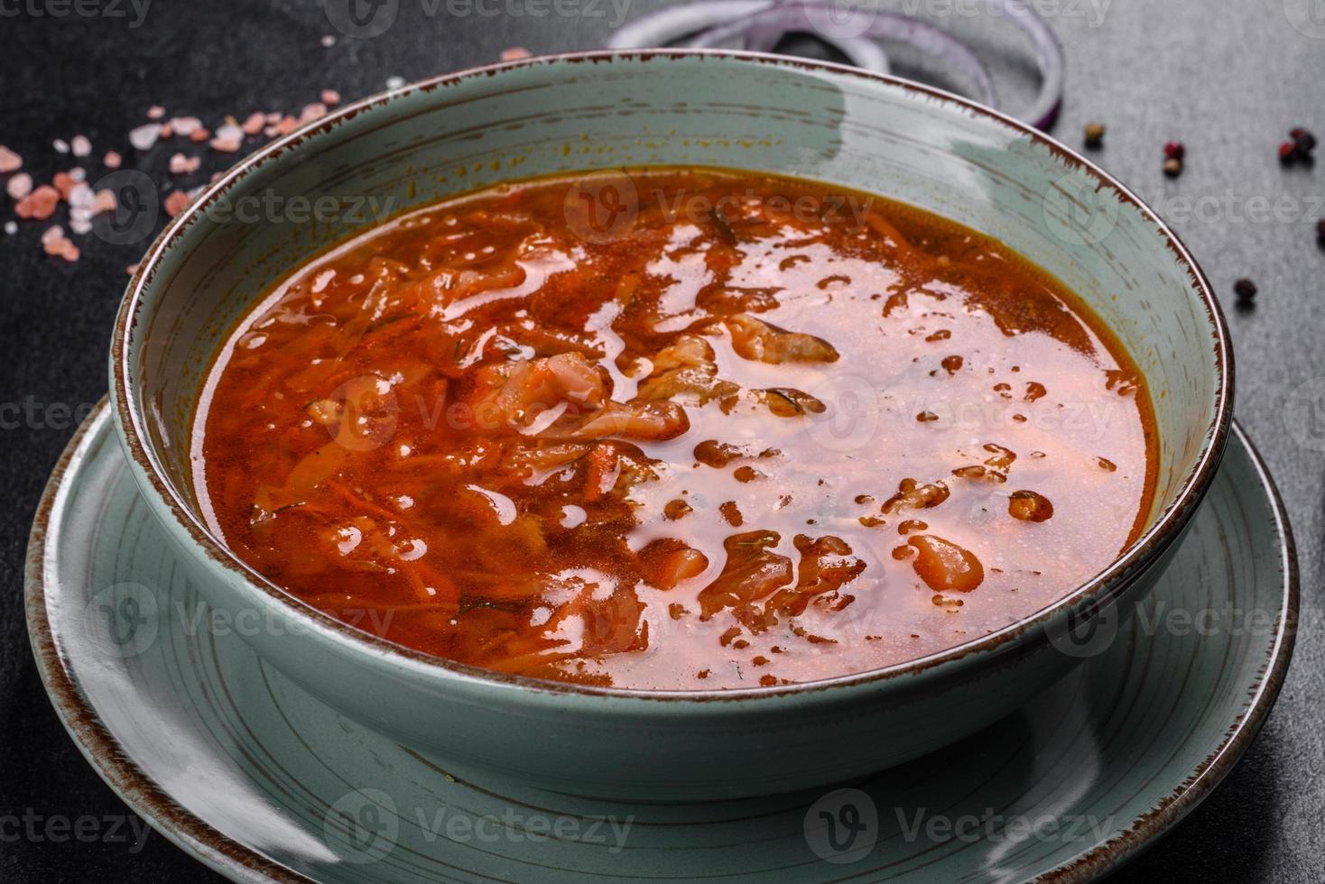 Delicioso borsch caliente con tomate y carne en un plato de cerámica foto