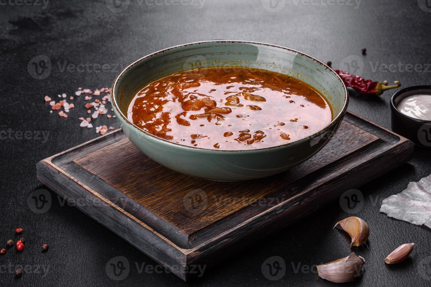 Delicious fresh hot borsch with tomato and meat in a ceramic plate photo