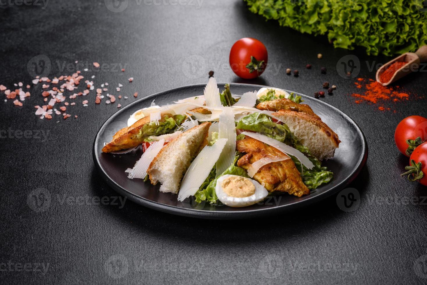 Delicious fresh caesar salad with chicken meat, breadcrumbs, tomatoes and lettuce leaves photo