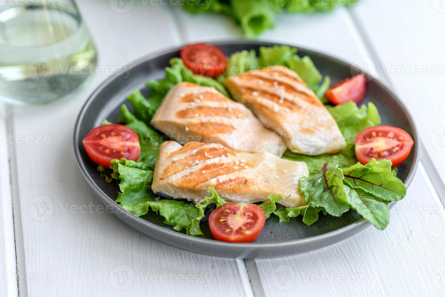 Delicious fresh salad with fish, tomatoes and lettuce leaves photo