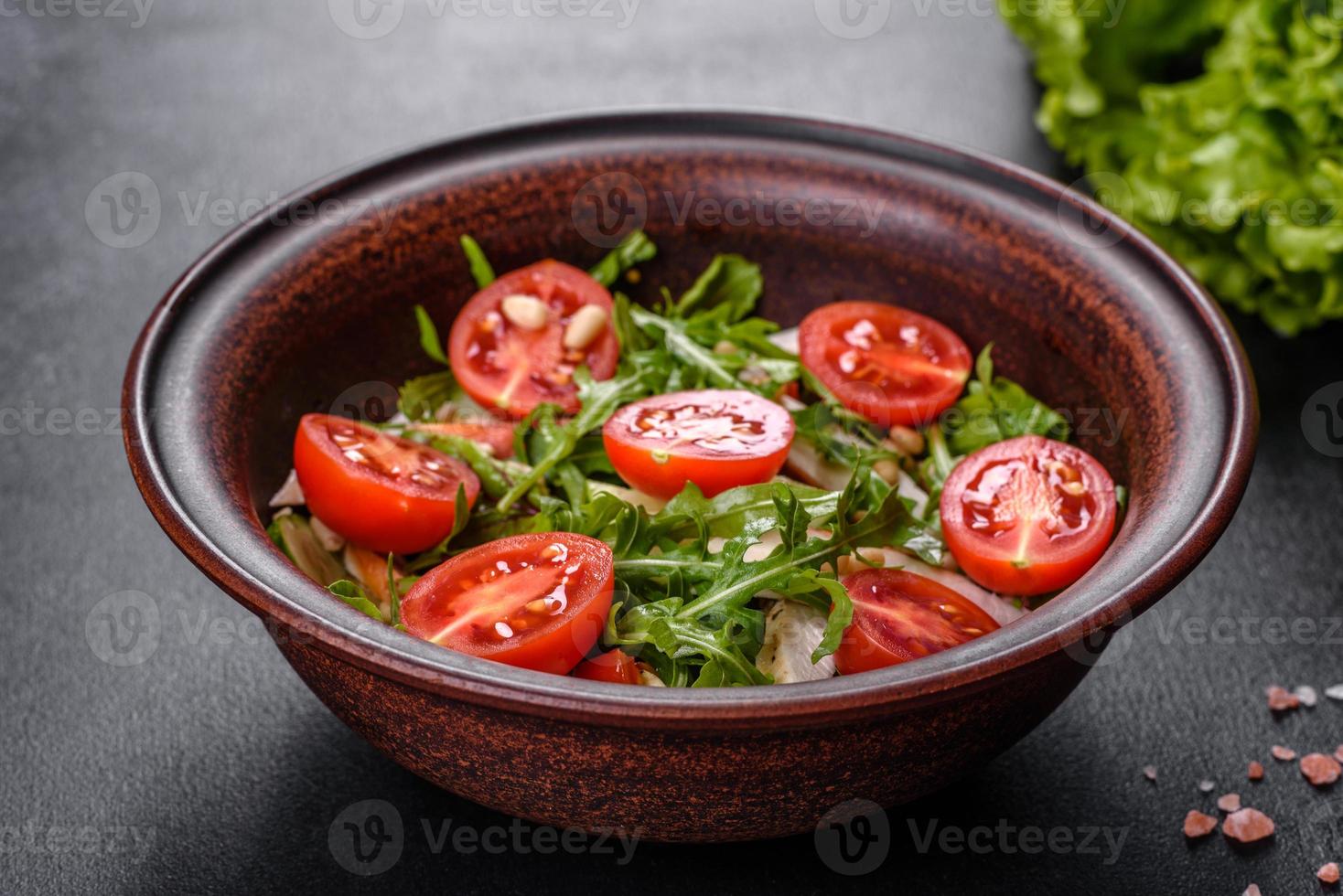 Trozos de pollo, tomates y hojas de lechuga sobre un fondo de hormigón oscuro foto