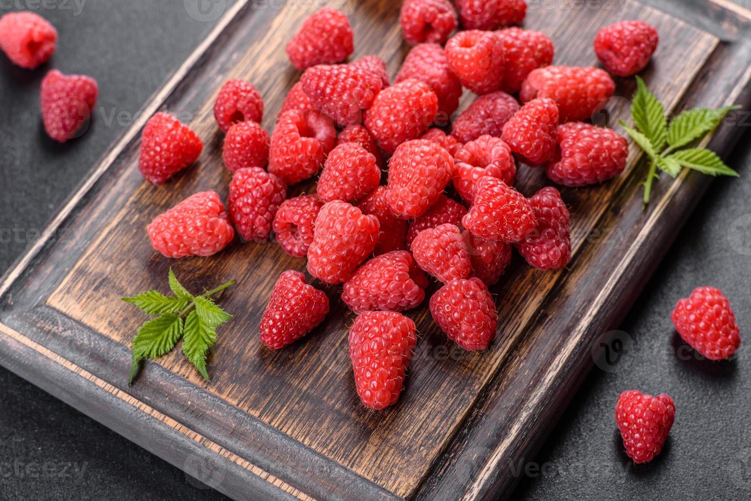 Delicious fresh juicy red raspberries on a dark table photo