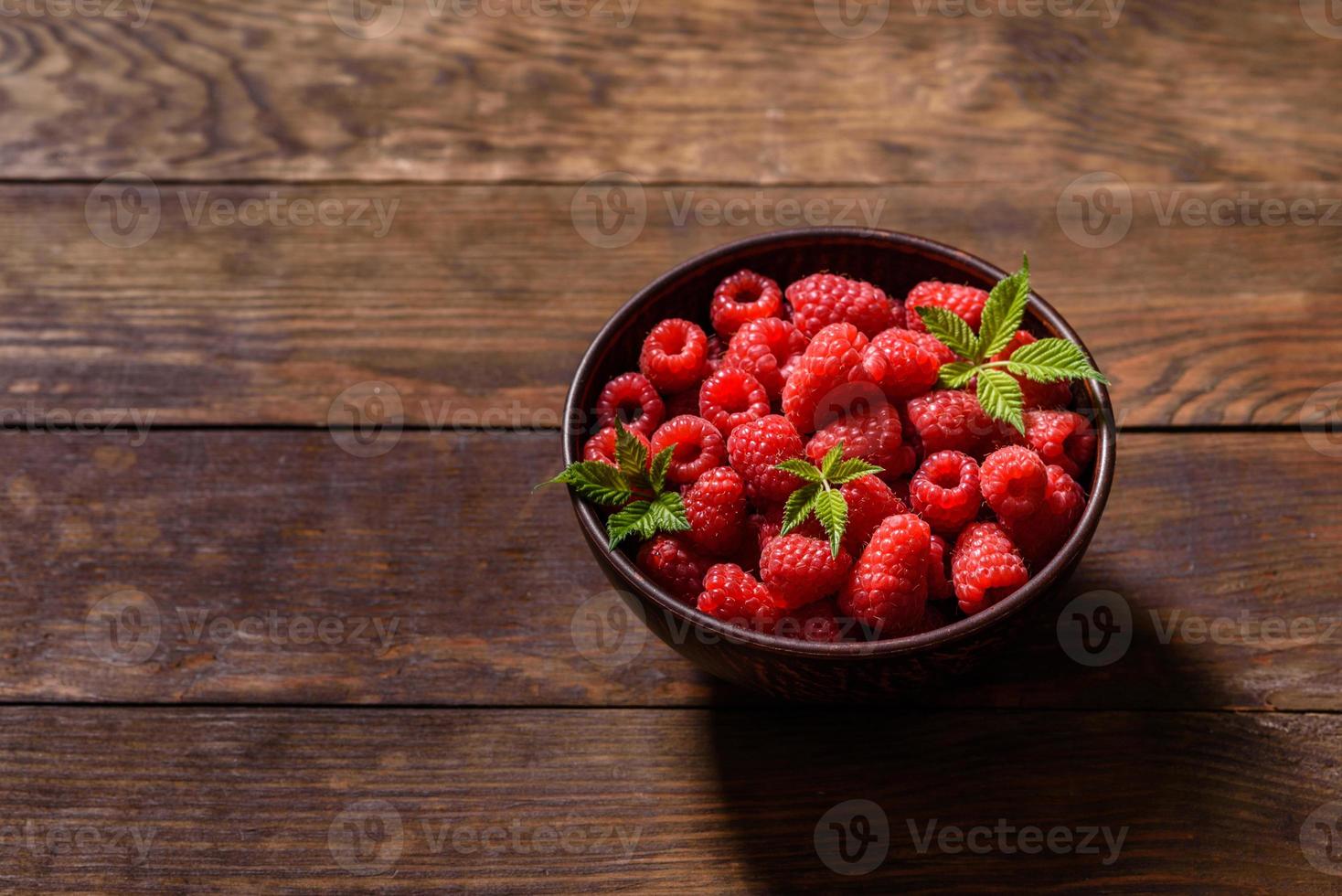 Deliciosas frambuesas rojas jugosas frescas sobre una mesa oscura foto