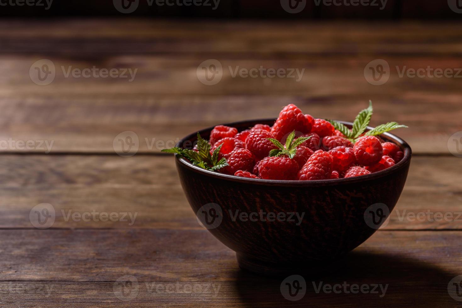 Deliciosas frambuesas rojas jugosas frescas sobre una mesa oscura foto