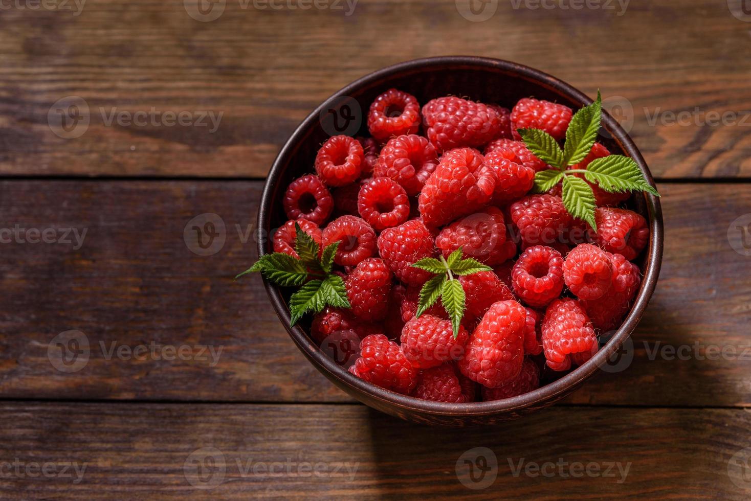 Deliciosas frambuesas rojas jugosas frescas sobre una mesa oscura foto