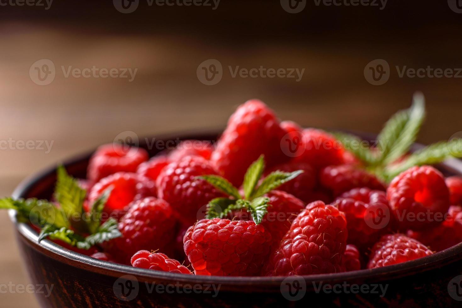 Delicious fresh juicy red raspberries on a dark table photo