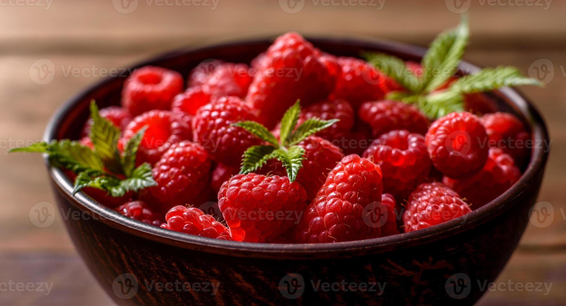 Deliciosas frambuesas rojas jugosas frescas sobre una mesa oscura foto