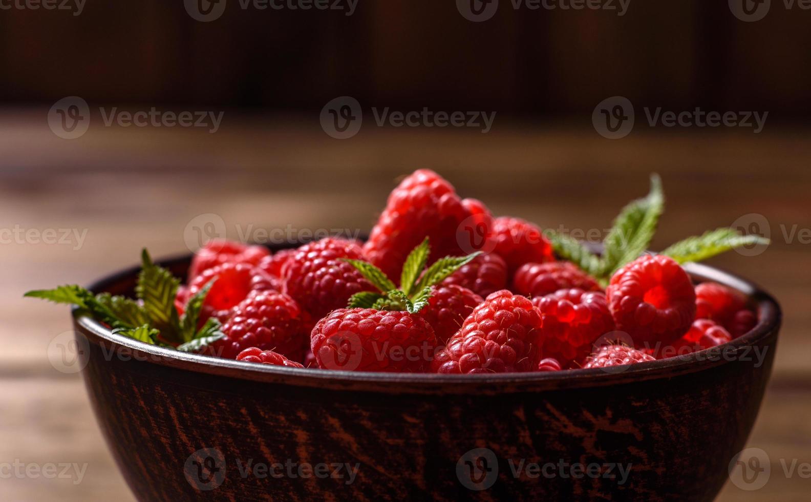 Delicious fresh juicy red raspberries on a dark table photo