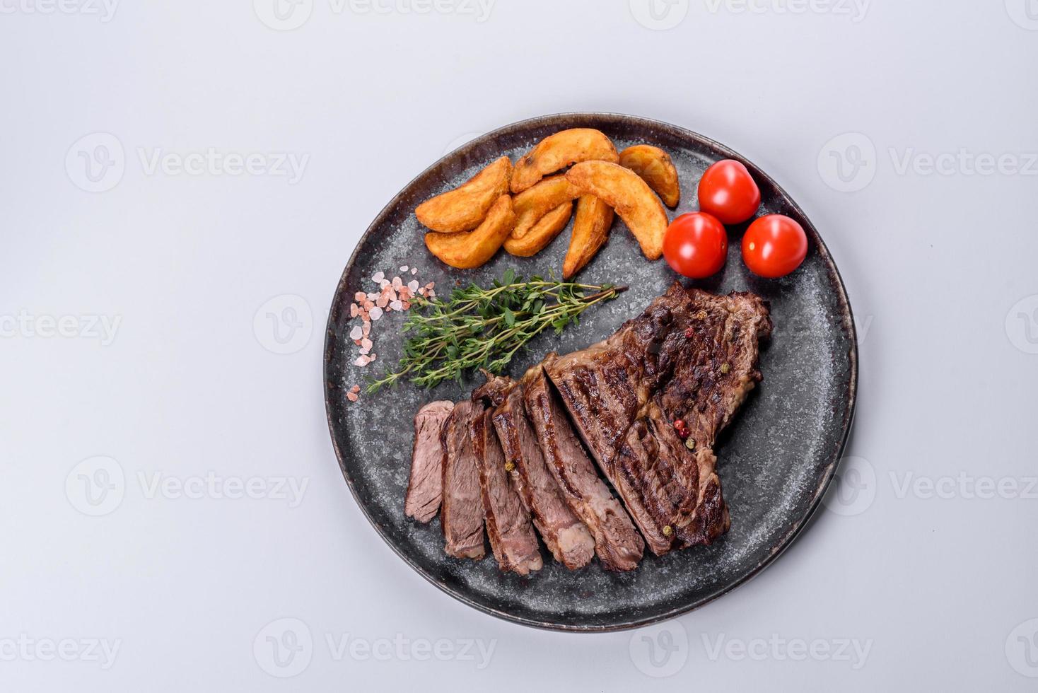 Delicioso bistec de ternera fresca jugosa con especias y hierbas sobre un fondo blanco. foto