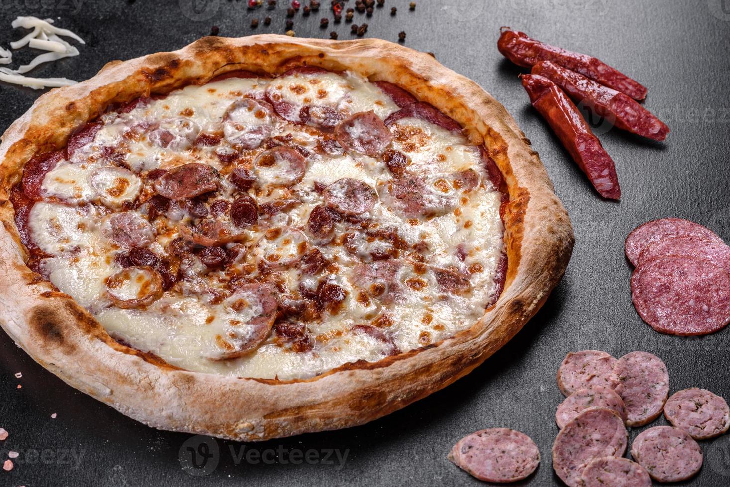 Fresh delicious Italian pizza with four types of meat on a dark concrete background photo