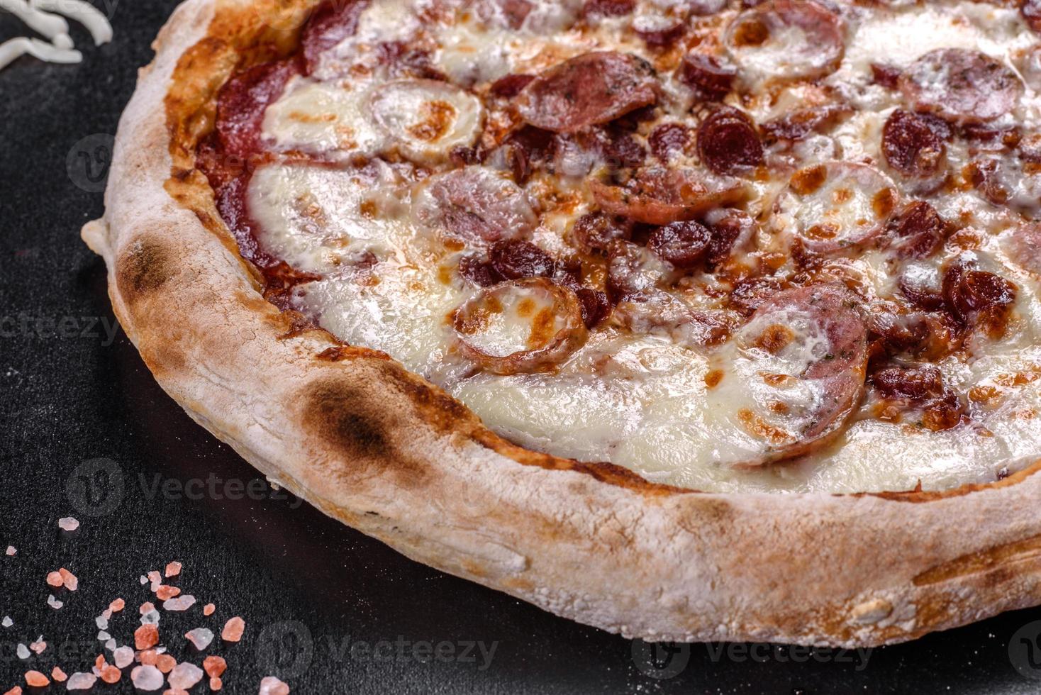 Deliciosa pizza italiana fresca con cuatro tipos de carne sobre un fondo de hormigón oscuro foto