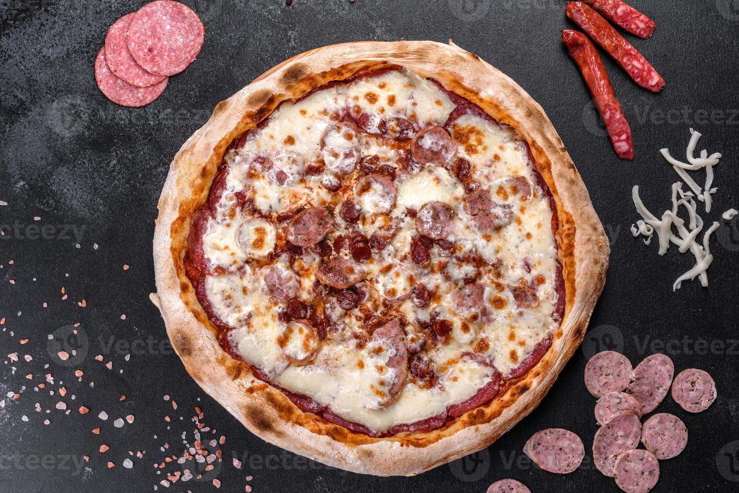 Deliciosa pizza italiana fresca con cuatro tipos de carne sobre un fondo de hormigón oscuro foto