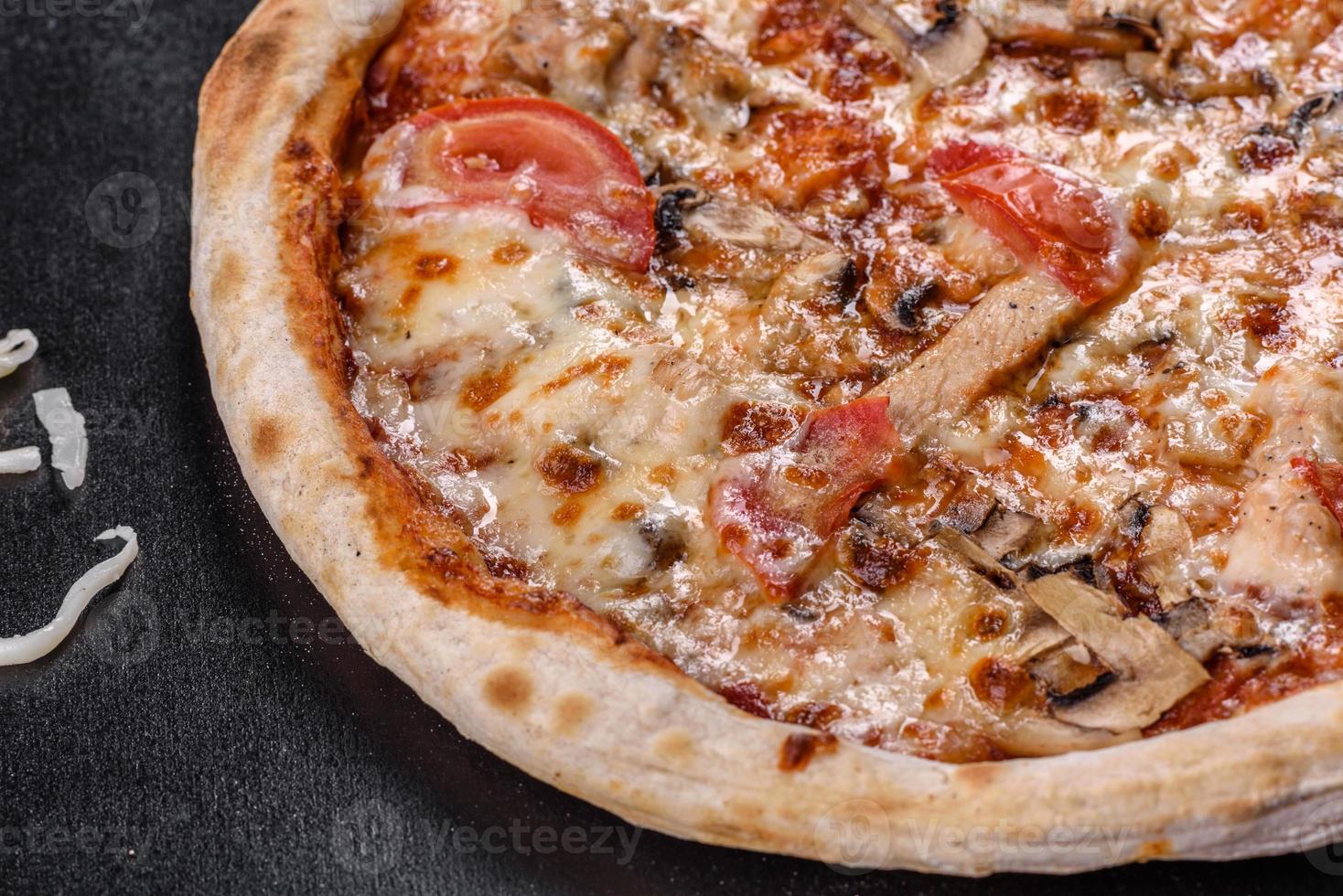 Deliciosa pizza italiana fresca con champiñones y tomates sobre un fondo de hormigón oscuro foto