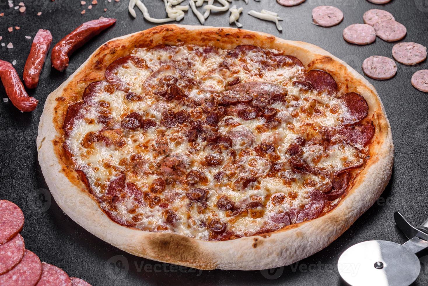 Deliciosa pizza italiana fresca con cuatro tipos de carne sobre un fondo de hormigón oscuro foto