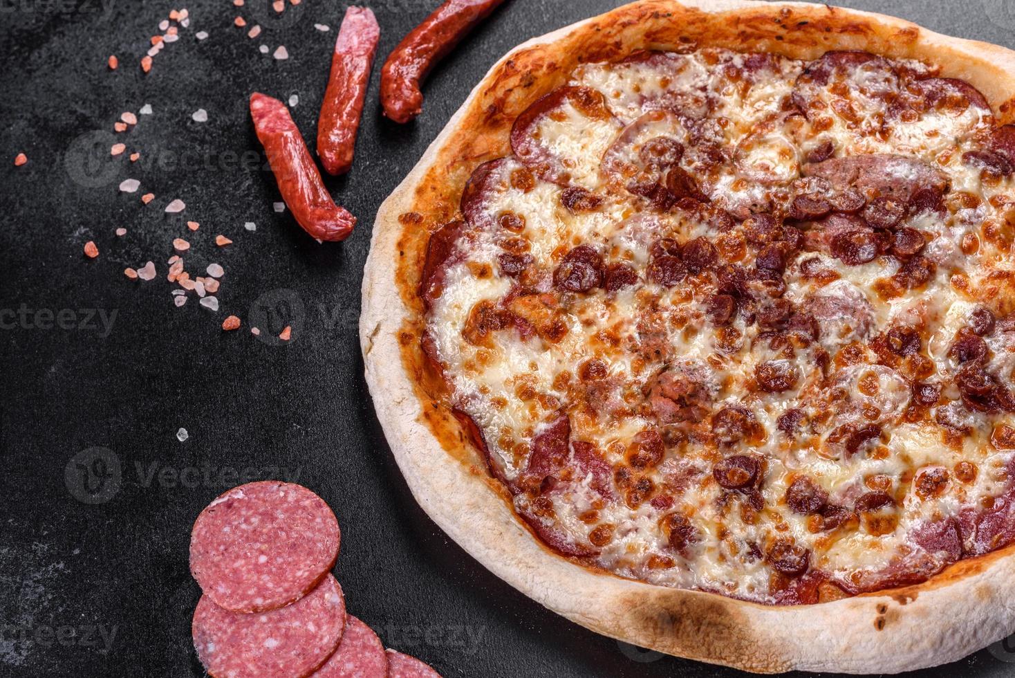 Fresh delicious Italian pizza with four types of meat on a dark concrete background photo