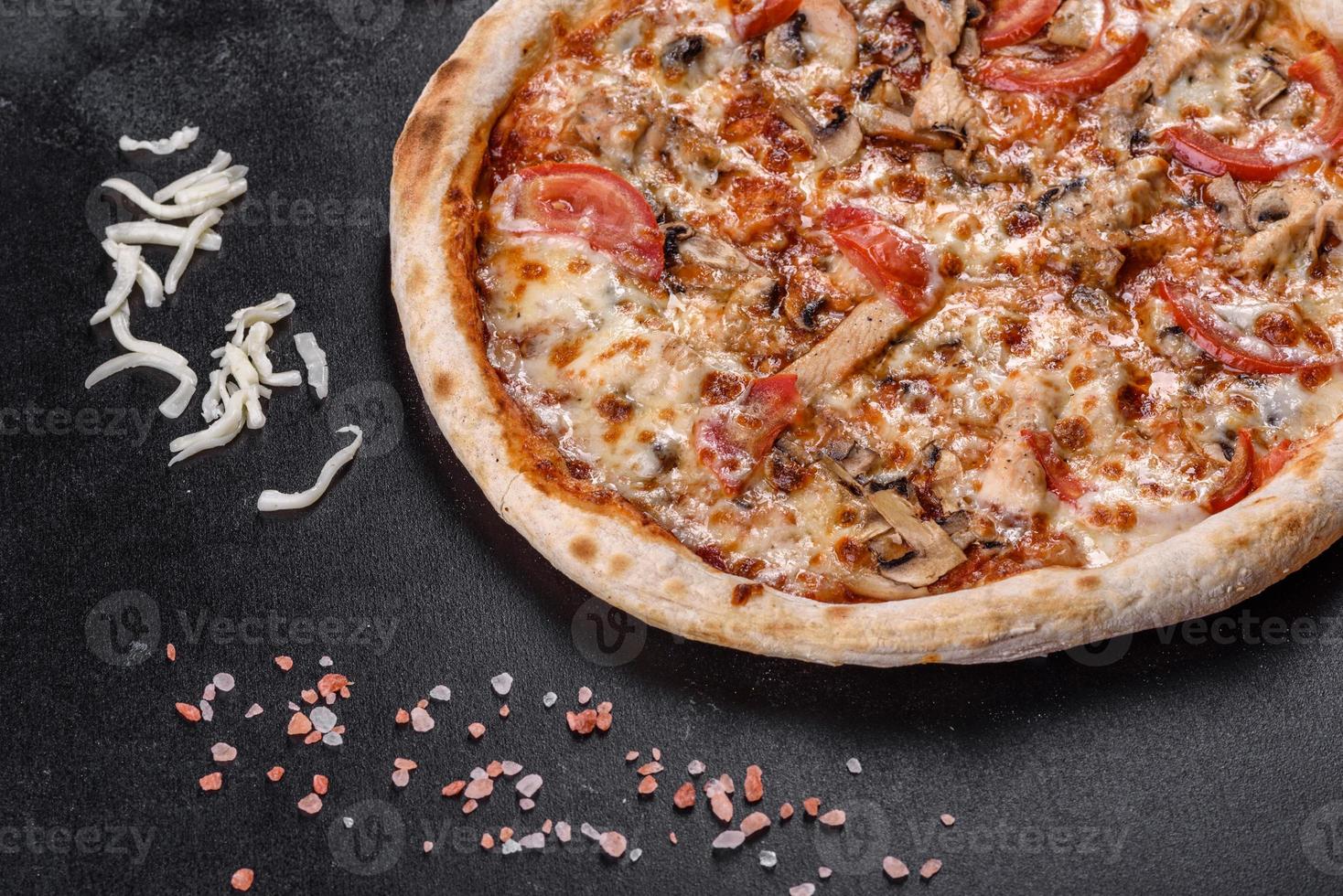 Fresh delicious Italian pizza with mushrooms and tomatoes on a dark concrete background photo