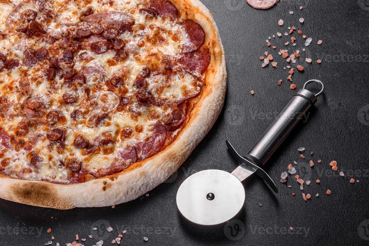 Fresh delicious Italian pizza with four types of meat on a dark concrete background photo