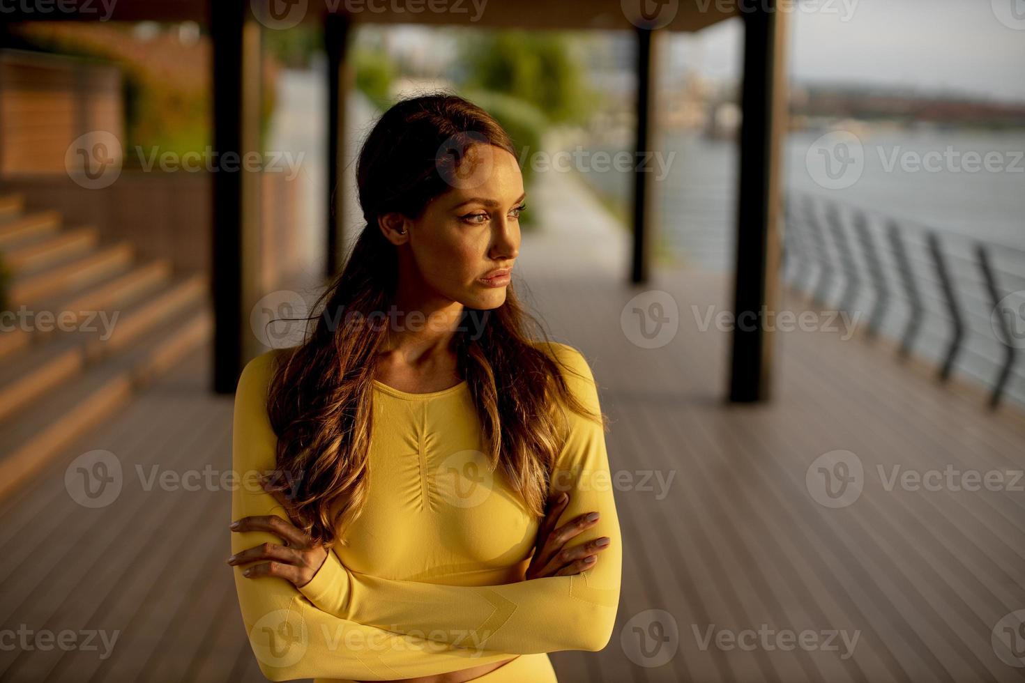 Mujer joven descansando durante el entrenamiento después de trotar foto