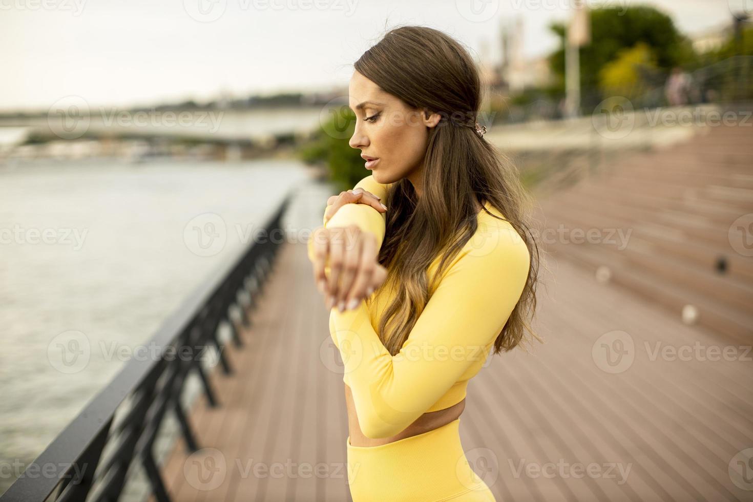 Young woman stretching on the riverside photo