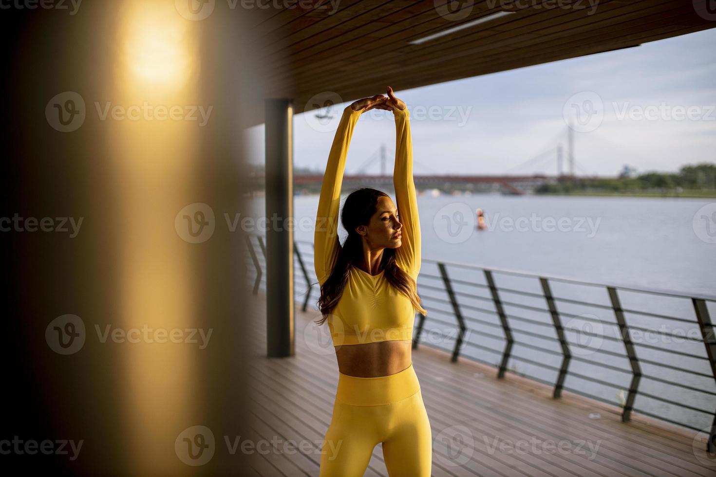 Young woman stretching on the riverside photo