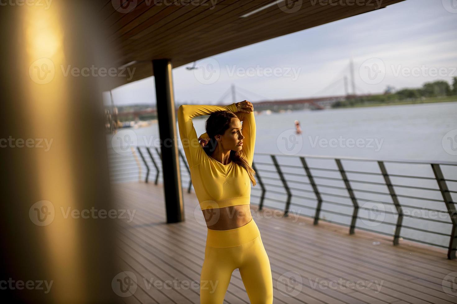 Young woman stretching on the riverside photo