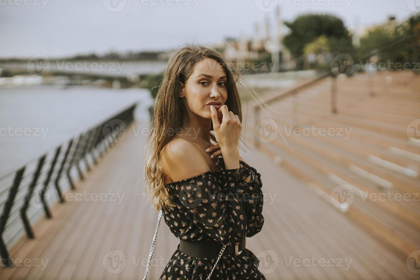 Young long hair brunette woman walking on the riverside photo