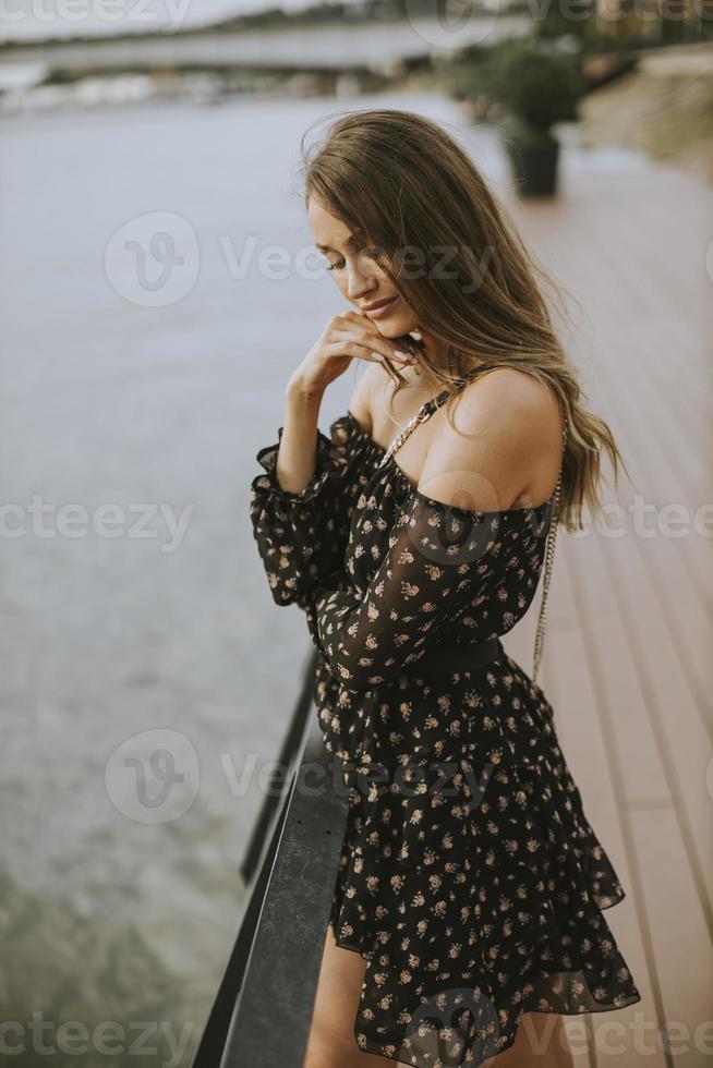 Joven mujer morena de pelo largo de pie en la orilla del río foto