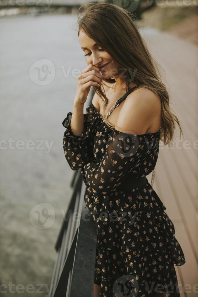 Young long hair brunette woman standing on the riverside photo