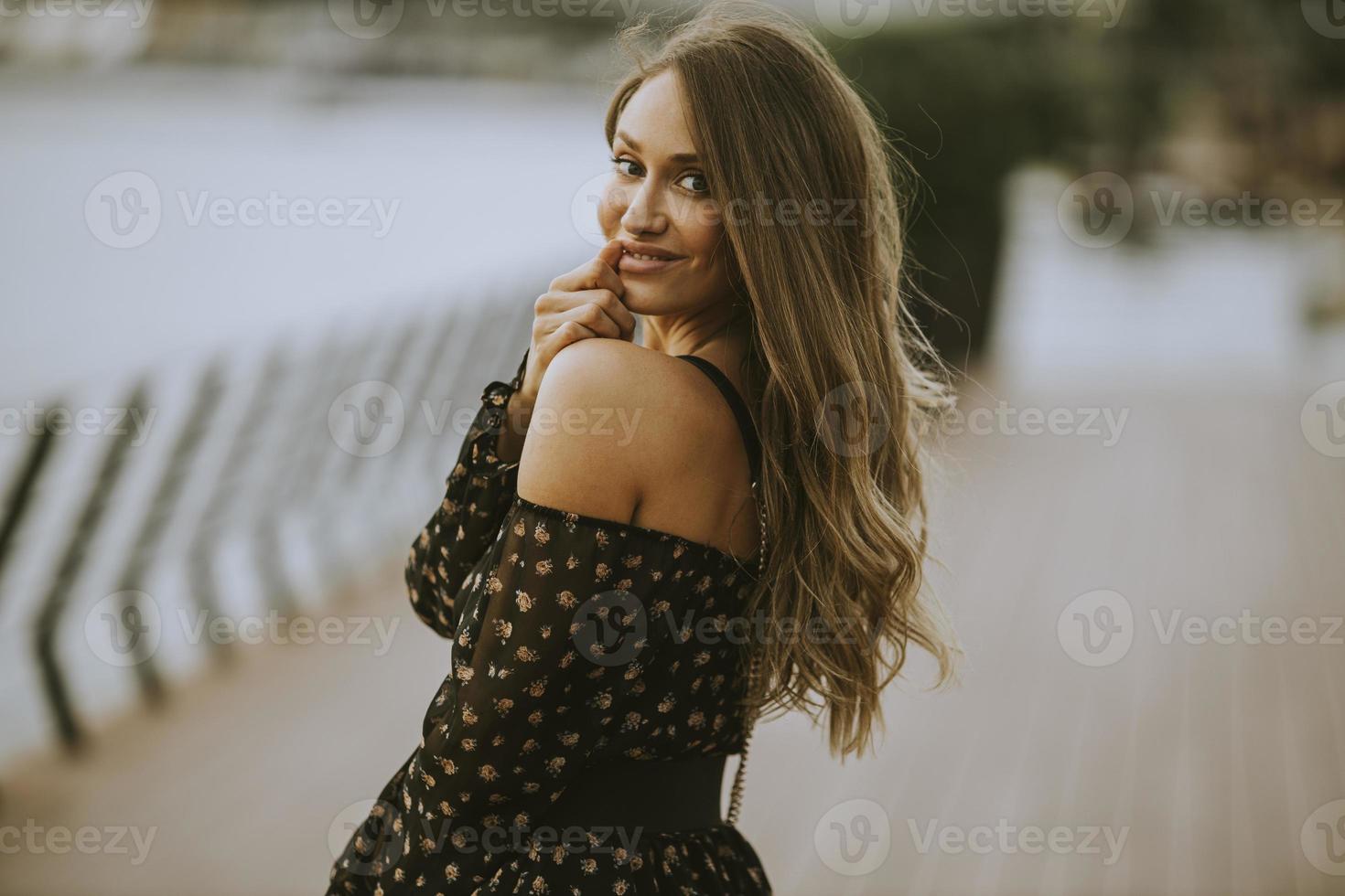 Young long hair brunette woman walking on the riverside photo