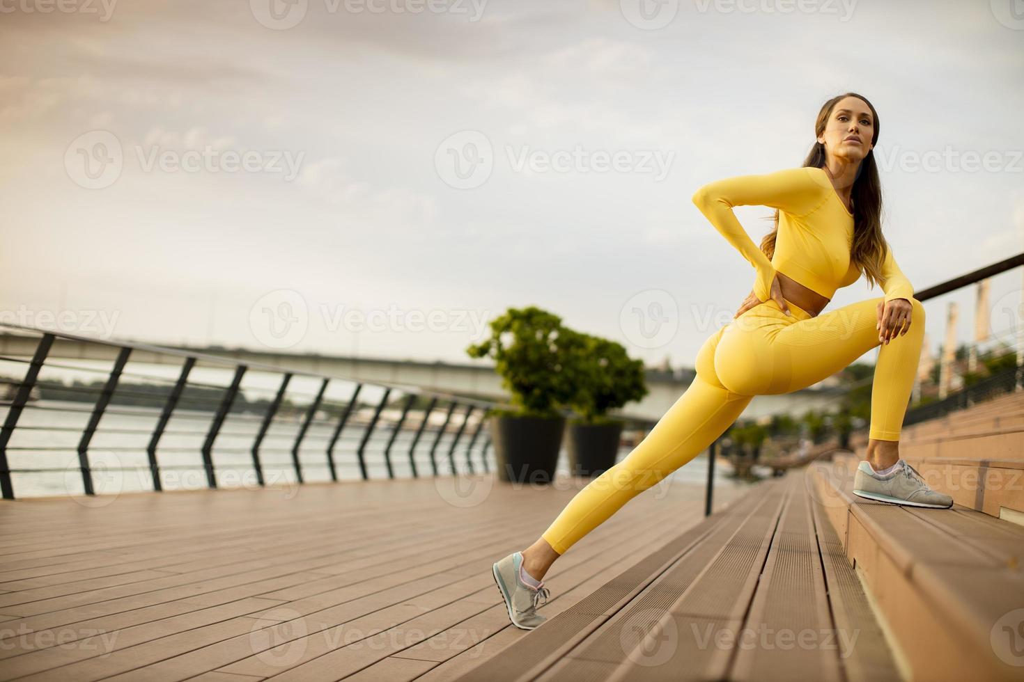 Young woman stretching on the riverside photo