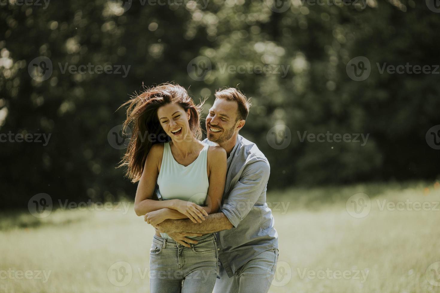 Afectuosa pareja joven divirtiéndose en la hierba verde foto