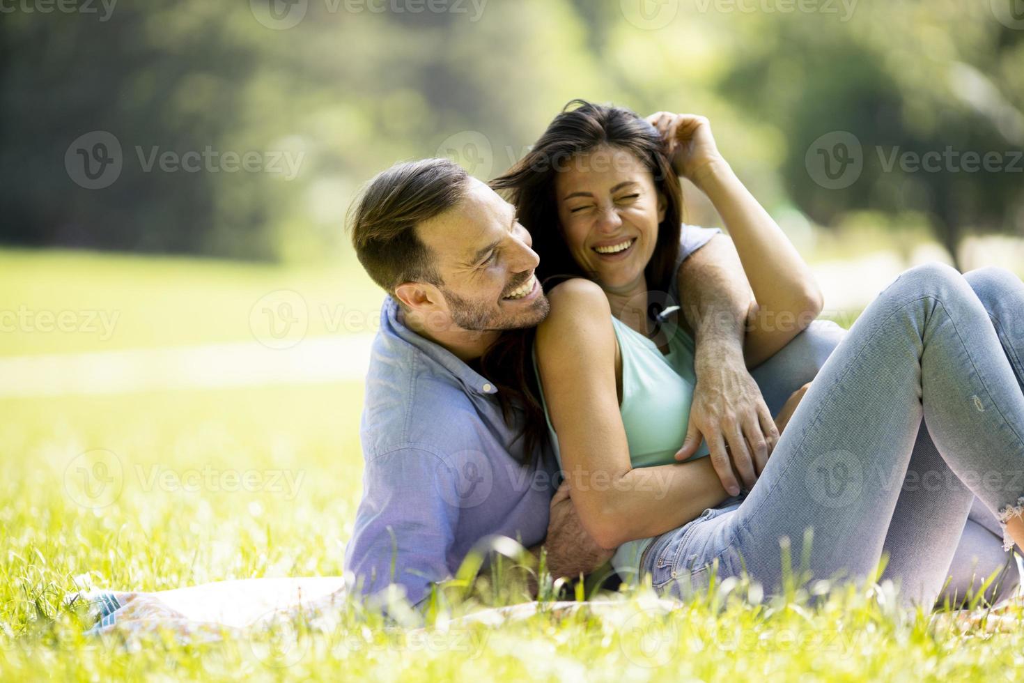 Affectionate young couple sitting on the green grass photo