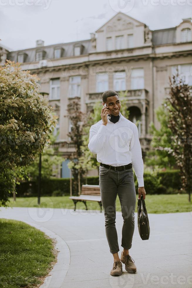 Joven empresario afroamericano mediante un teléfono móvil en una calle foto