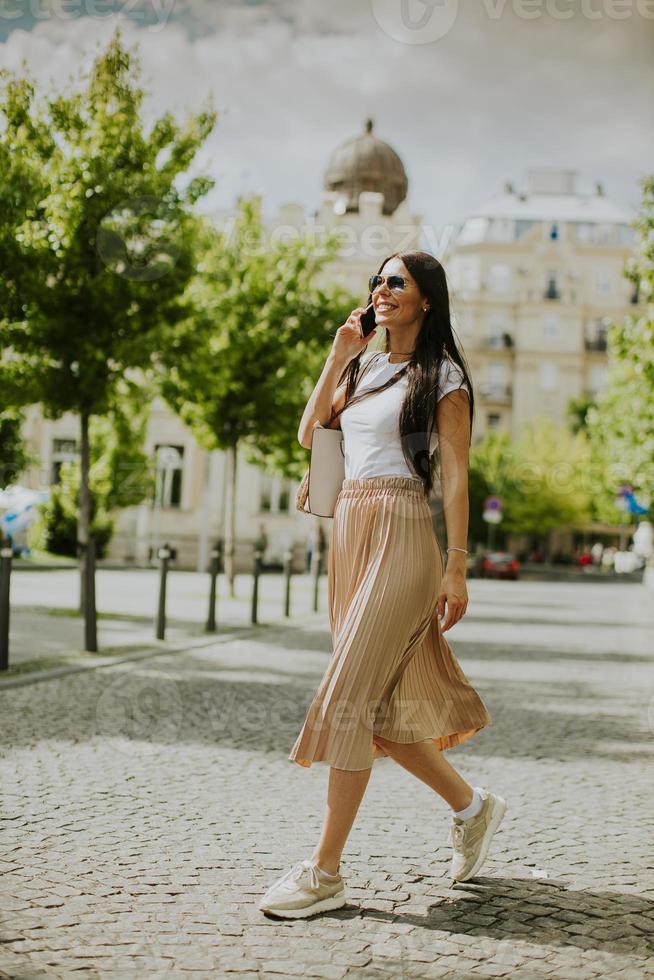 Young woman using a mobile phone while walking on the street photo