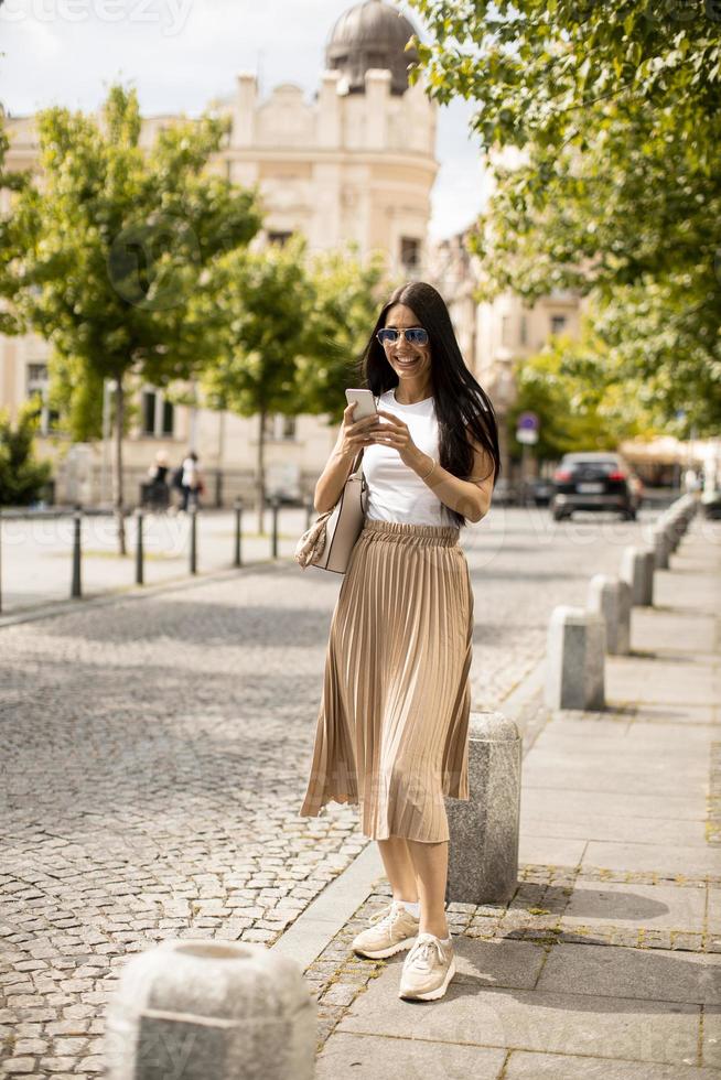 Young woman using a mobile phone while walking on the street photo